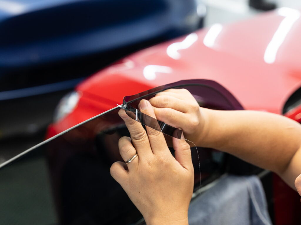 Professional installer applying tint film to a car window at Shell Shocked Wraps